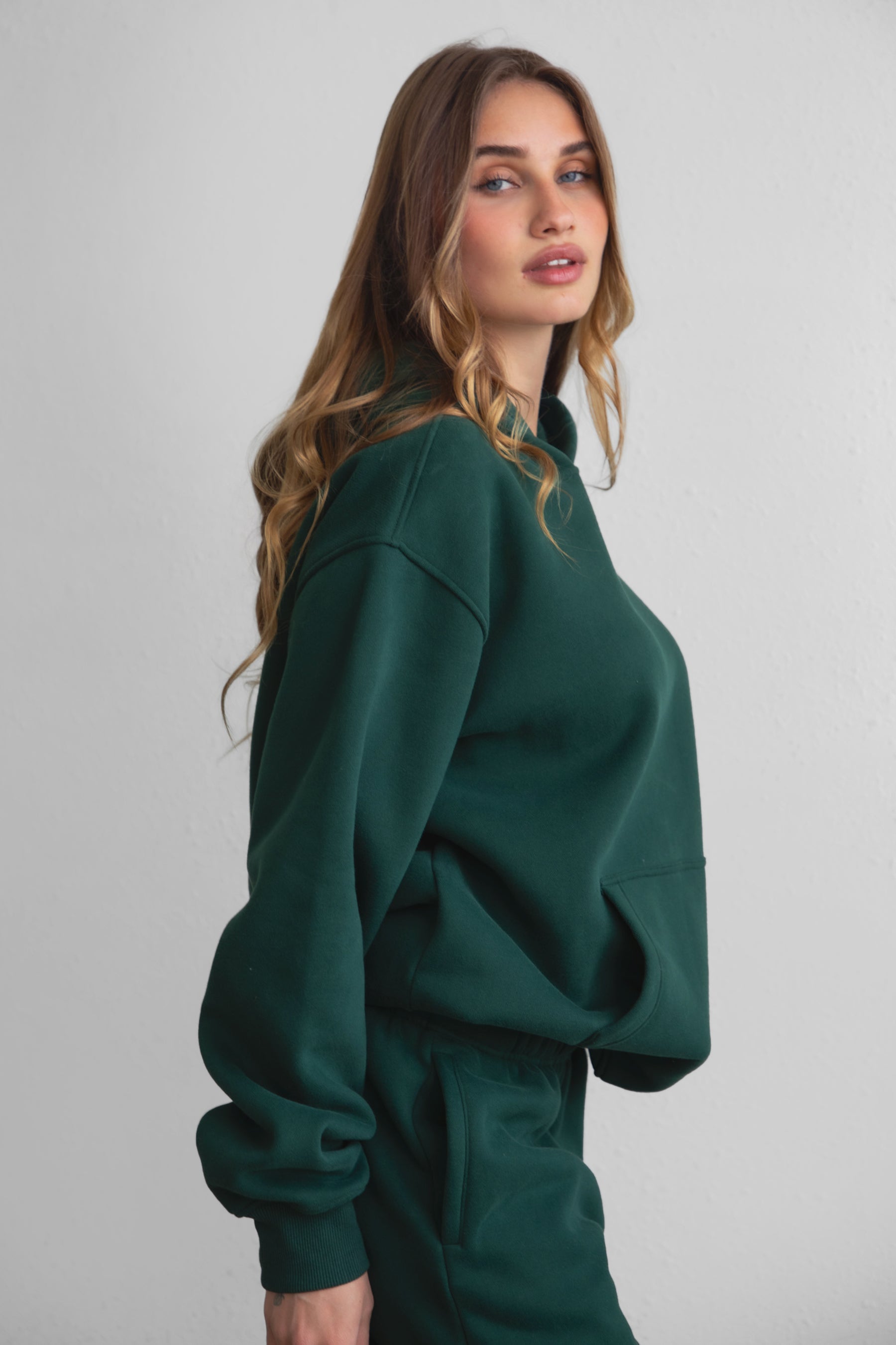 Woman wearing the TIC TOC TJ31007 DAMI forrest green cloud fleece oversized hoodie featuring a dropped shoulder design, kangaroo pocket, and ribbed cuffs with matching bottoms.