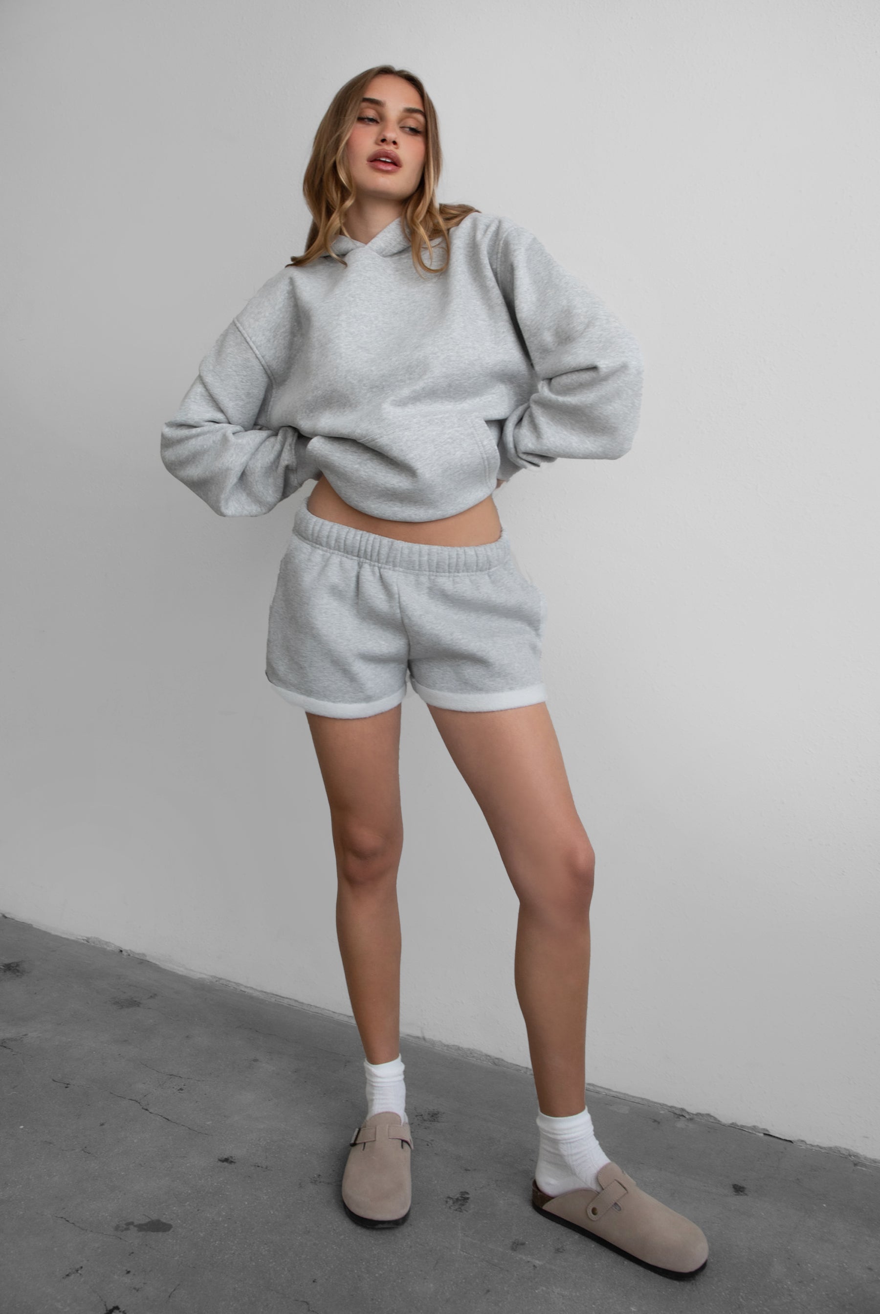 Woman wearing the TIC TOC TJ31007 DAMI heather grey cloud fleece oversized hoodie featuring a dropped shoulder design, kangaroo pocket, and ribbed cuffs with matching bottoms.