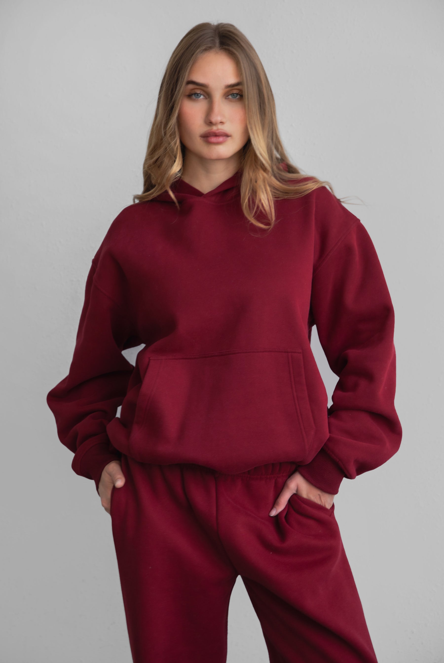 Woman wearing the TIC TOC TJ31007 DAMI maroon cloud fleece oversized hoodie featuring a dropped shoulder design, kangaroo pocket, and ribbed cuffs with matching bottoms.