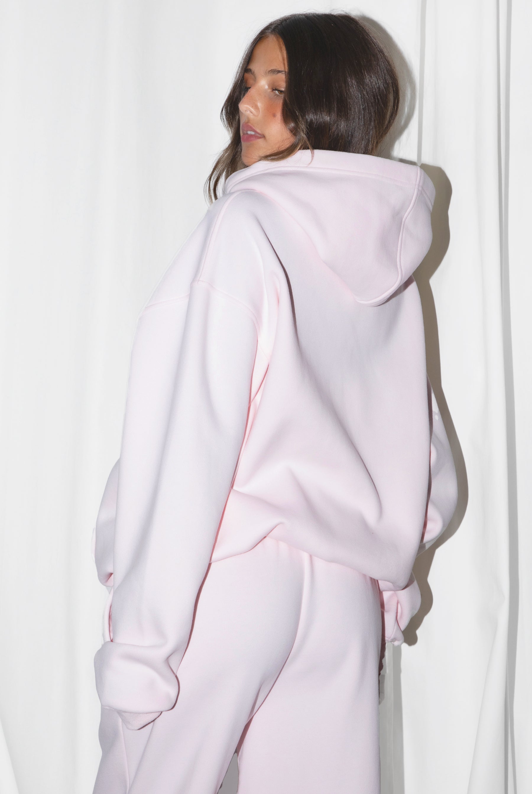 Woman wearing the TIC TOC TJ31007 DAMI pale pink cloud fleece oversized hoodie featuring a dropped shoulder design, kangaroo pocket, and ribbed cuffs with matching bottoms.