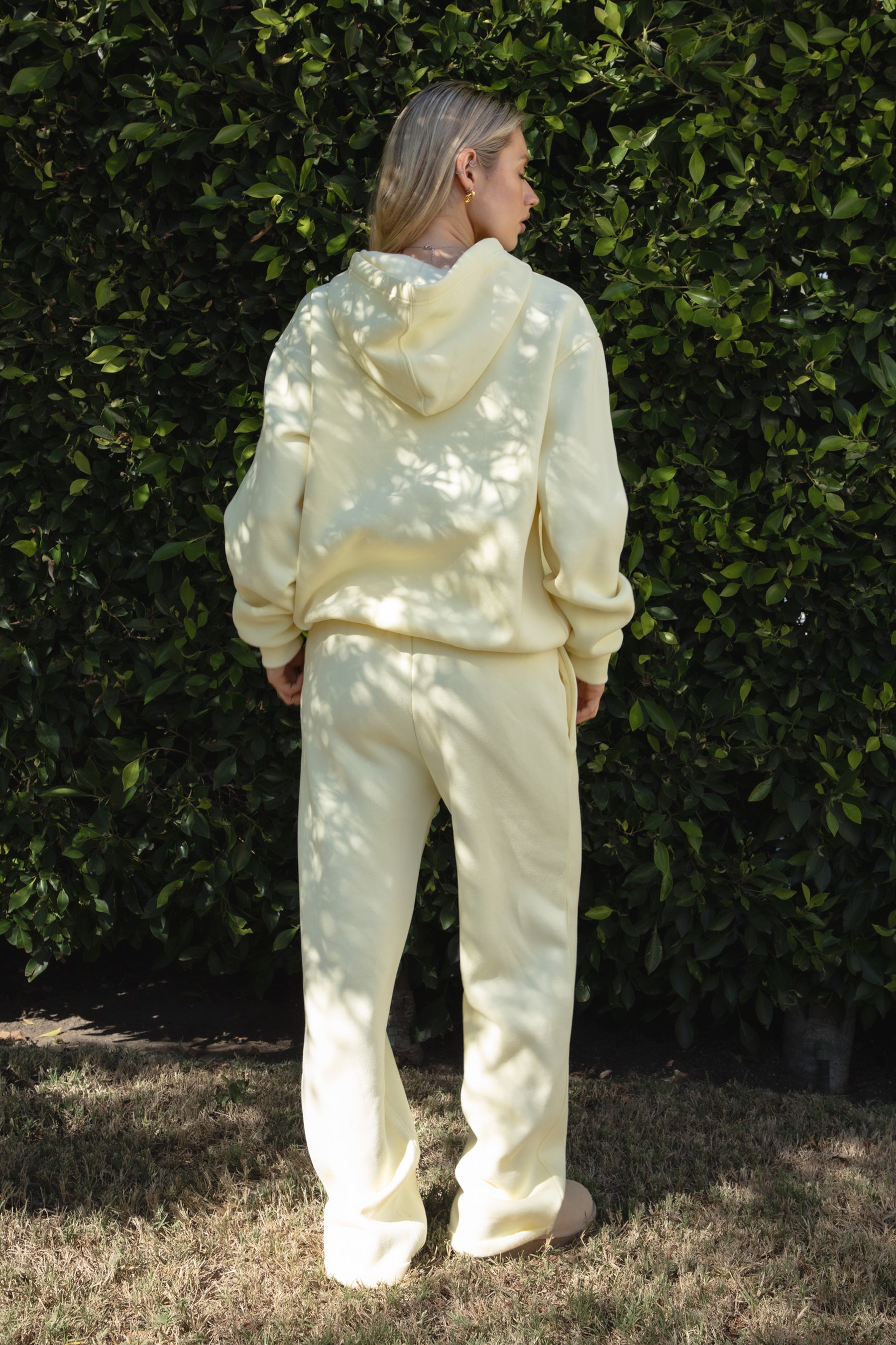 Woman wearing the TIC TOC TJ31007 DAMI pale yellow cloud fleece oversized hoodie featuring a dropped shoulder design, kangaroo pocket, and ribbed cuffs with matching bottoms.