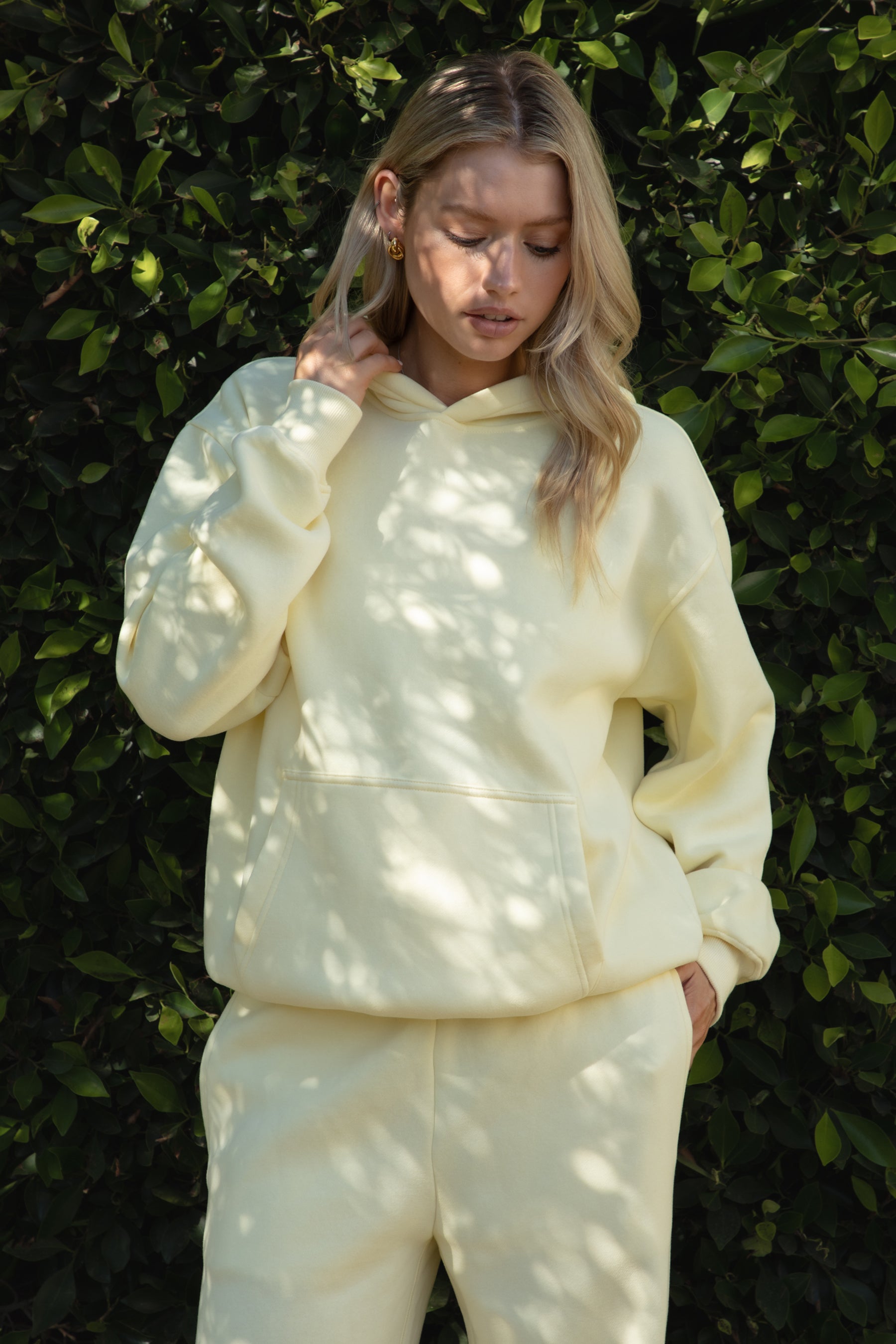 Woman wearing the TIC TOC TJ31007 DAMI pale yellow cloud fleece oversized hoodie featuring a dropped shoulder design, kangaroo pocket, and ribbed cuffs with matching bottoms.