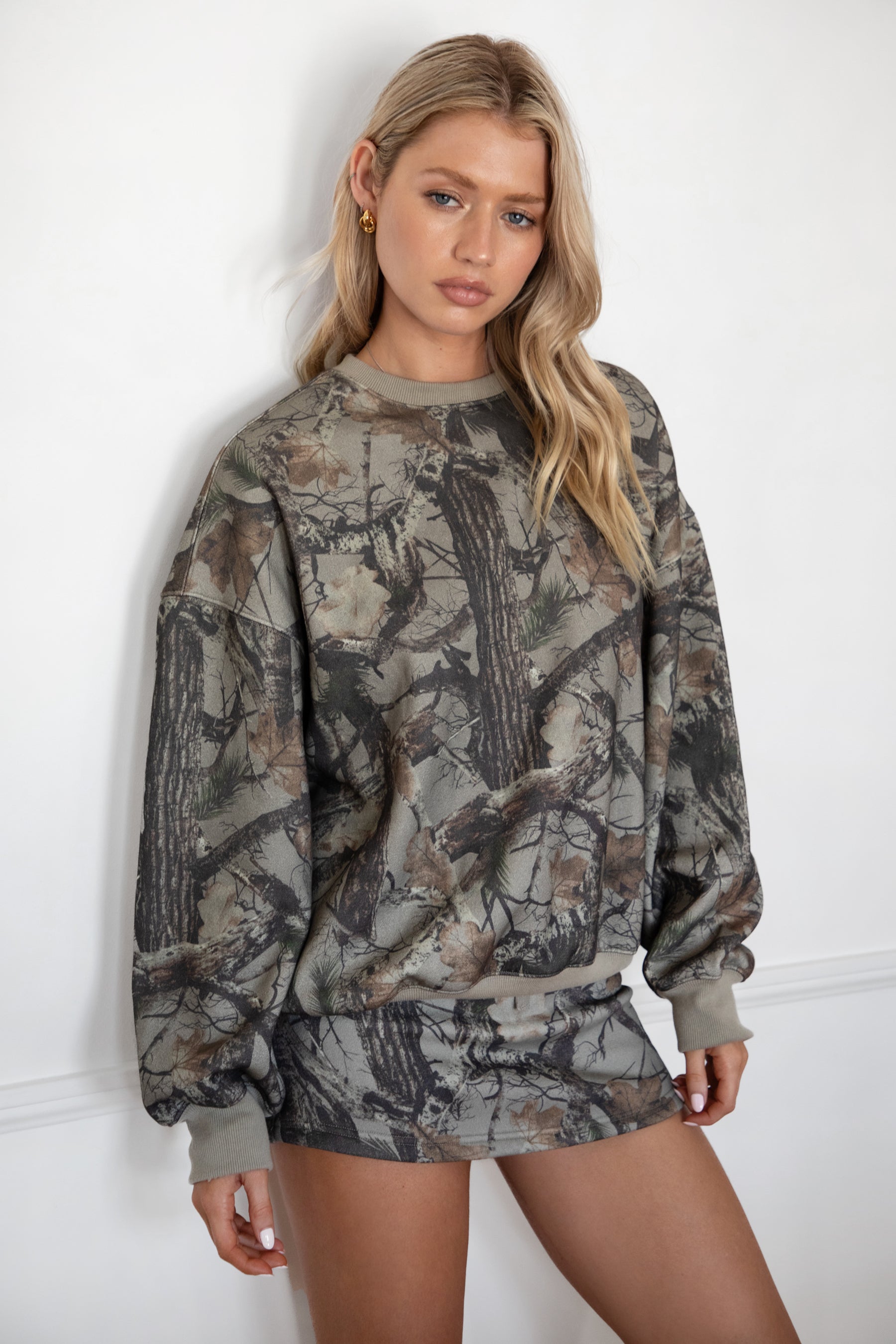 Woman wearing a camouflage outfit against a white background