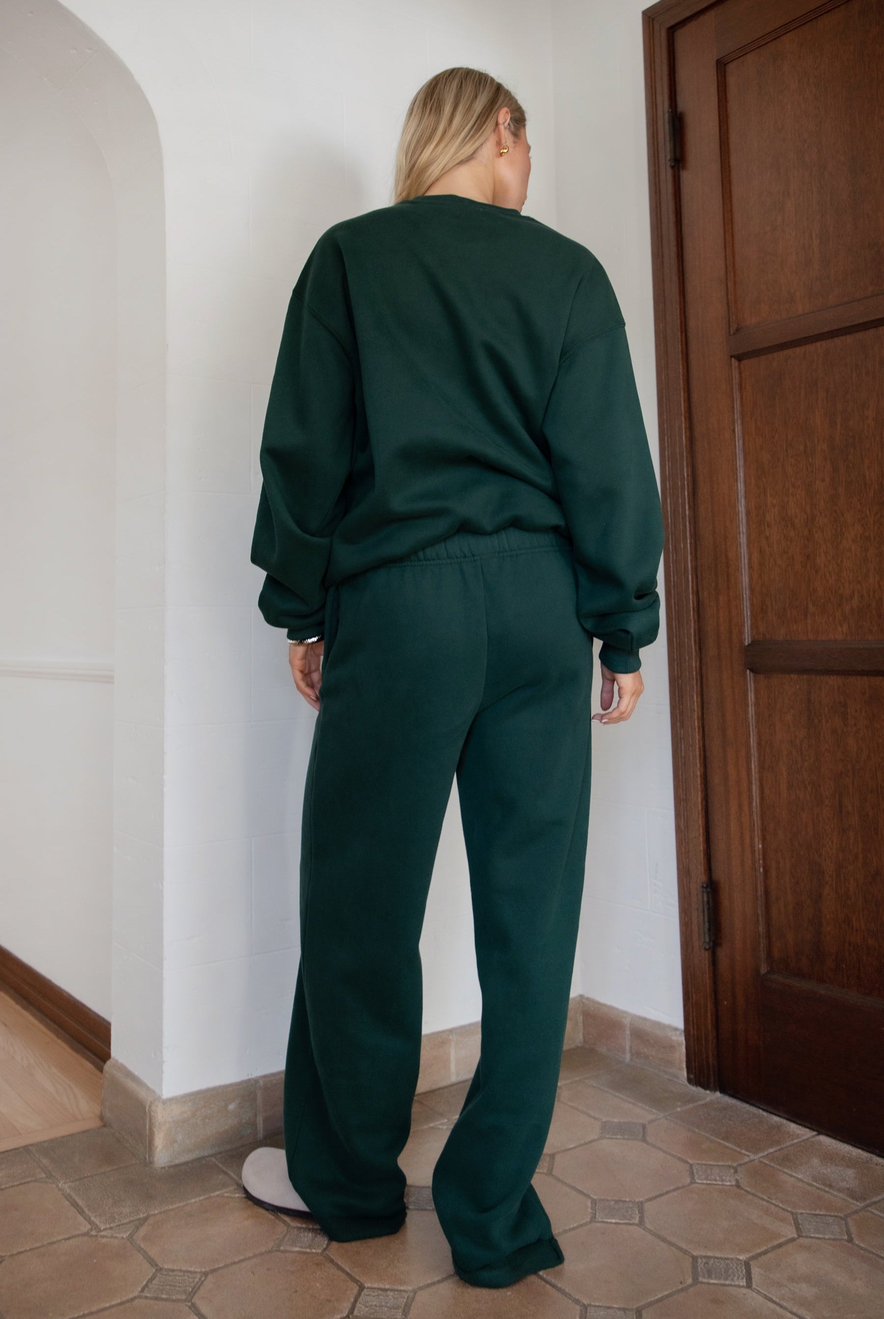Woman wearing the TIC TOC TJ31656 LANI forrest green cloud fleece crew neck pullover sweatshirt featuring dropped shoulders, ribbed trim, and cozy fleece fabric with the matching bottoms