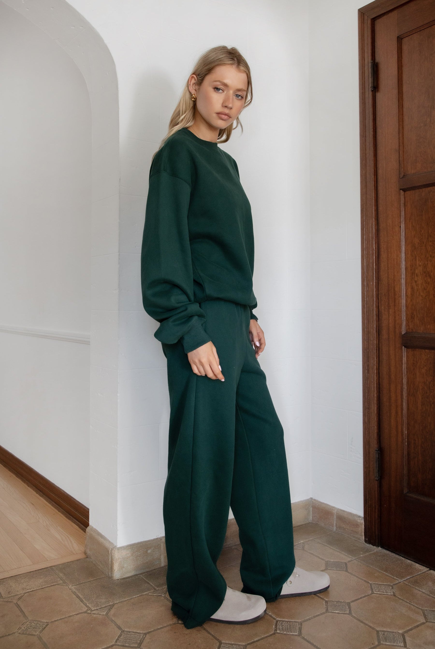 Woman wearing the TIC TOC TJ31656 LANI forrest green cloud fleece crew neck pullover sweatshirt featuring dropped shoulders, ribbed trim, and cozy fleece fabric with the matching bottoms .