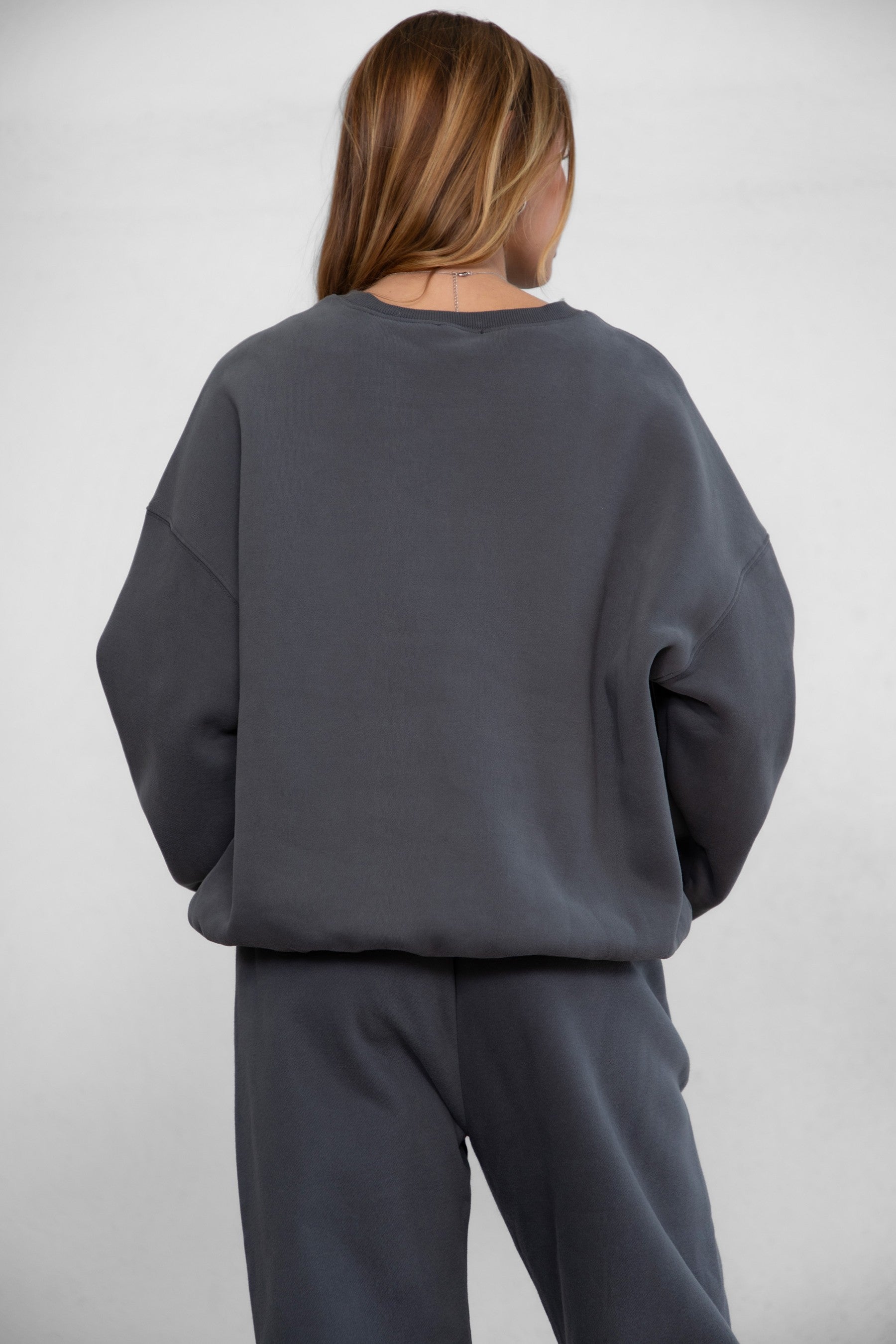 Person wearing a gray sweatshirt and pants on a white background