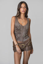 Woman wearing TIC TOC TA31107 REAGAN washed denim western bustier top featuring a low V neckline, floral embroidered bodice, adjustable straps, and hook-and-eye front closure, styled outdoors with western-inspired accessories for a modern cowgirl aesthetic.