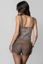 Woman wearing TIC TOC TA31107 REAGAN washed denim western bustier top featuring a low V neckline, floral embroidered bodice, adjustable straps, and hook-and-eye front closure, styled outdoors with western-inspired accessories for a modern cowgirl aesthetic.