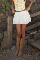 Woman wearing TIC TOC SA31409 YNES crinkle gauze tiered mini skort with built-in shorts, featuring a soft stretch smocked waist, easy pull-on fit, and airy semi-sheer gauze fabric for a boho spring and summer vacation look.
