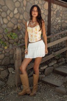 Woman wearing TIC TOC SA31409 YNES crinkle gauze tiered mini skort with built-in shorts, featuring a soft stretch smocked waist, easy pull-on fit, and airy semi-sheer gauze fabric for a boho spring and summer vacation look.