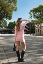 Woman wearing TIC TOC TSC30559 COZEE pink sweater knit two-piece set featuring a cropped zip-up hoodie with ribbed cuffs and waist, paired with a matching foldover waistband mini skirt with built-in shorts, styled outdoors with black knee-high boots and a small black shoulder bag.