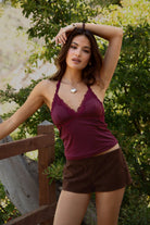 Woman wearing TIC TOC BENET DARK BRWON faux suede low-rise micro shorts featuring an ultra-soft suede texture, hidden side zipper, short length, and curve-hugging fit styled with a cozy knit top in a natural outdoor setting.