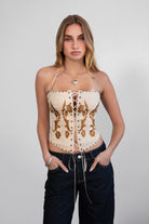 Model wearing the khaki CLEMENTINE embroidered western corset top with halter tie and lace-up front, styled for a modern cowgirl festival outfit