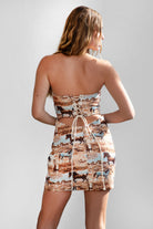 Woman wearing a strapless dress with horse print on a plain background