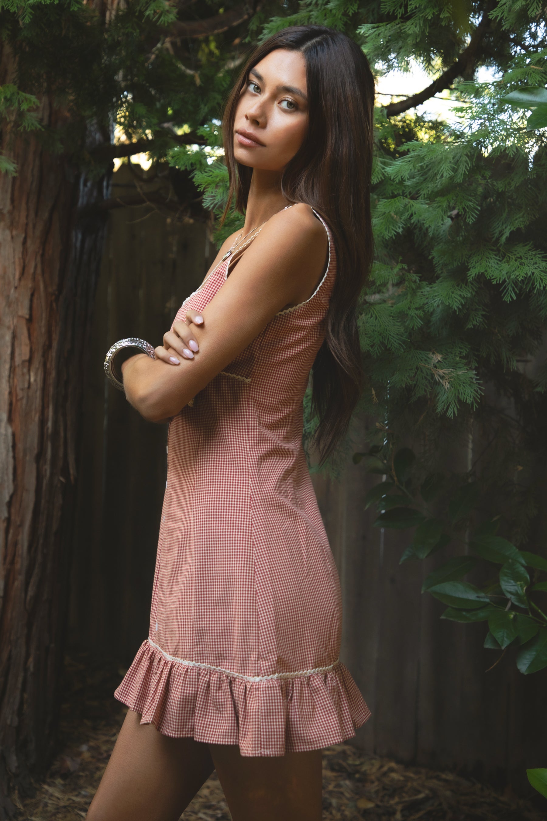 Woman wearing TIC TOC DA31931-AMELIE AMELIE gingham mini dress featuring a square scoop neckline with picot trim, wide shoulder straps, front faux button detail, fitted bodice with under bust seam, ruffled hem mini skirt in gingham poplin fabric, and a clean back zipper closure, styled with simple accessories for a coquette, western-sweet summer look.