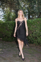 Woman wearing TIC TOC DA31971 LINORA satin lace contrast V-neck mini dress featuring a soft satin body, scalloped lace trim at the neckline, thin adjustable straps, asymmetrical lace-trim hem, and side slit detail for a sleek feminine night-out look.