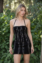 Woman wearing TIC TOC DA32063 ELSIE stretch embroidered western mini halter dress featuring a sculpted body-hugging fit, statement western-inspired embroidery, studded trim along the neckline and hem, halter self-tie closure, and mini length silhouette for a confident western-chic night-out look.