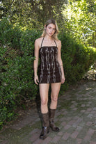 Woman wearing TIC TOC DA32063 ELSIE stretch embroidered western mini halter dress featuring a sculpted body-hugging fit, statement western-inspired embroidery, studded trim along the neckline and hem, halter self-tie closure, and mini length silhouette for a confident western-chic night-out look.