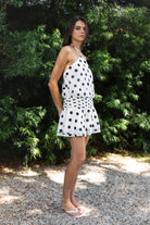 Woman wearing BIJOO polka dot chiffon halter mini dress featuring flowy chiffon fabric, bold polka dot print, adjustable self tie halter neckline, open back silhouette, relaxed blouson bodice, ruched waistband detailing, layered flared mini skirt, and fully lined construction for comfortable coverage.