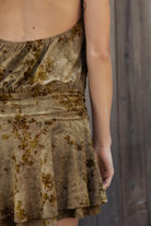 Woman wearing OLIVINE flocked sleeveless floral halter ruched mini dress featuring soft flocked jersey fabric, stretch jersey lining, smocked high halter neckline, open back design, ruched drop waist, layered flounce mini skirt, and pull on construction for special occasion styling.