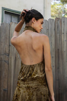 Woman wearing OLIVINE flocked sleeveless floral halter ruched mini dress featuring soft flocked jersey fabric, stretch jersey lining, smocked high halter neckline, open back design, ruched drop waist, layered flounce mini skirt, and pull on construction for special occasion styling.