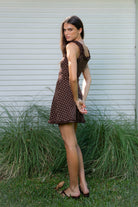 Woman wearing MOXI ruffle polka dot stretch mini dress featuring soft stretch cotton jersey fabric, allover polka dot print, scoop neckline with layered ruffle trim, wide ruffled shoulder straps, fitted bodice, softly flared skirt, and double ruffle trim along the mini hem.