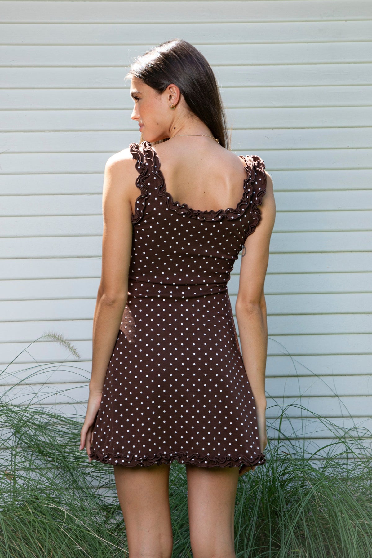 Woman wearing MOXI ruffle polka dot stretch mini dress featuring soft stretch cotton jersey fabric, allover polka dot print, scoop neckline with layered ruffle trim, wide ruffled shoulder straps, fitted bodice, softly flared skirt, and double ruffle trim along the mini hem.