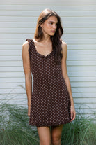 Woman wearing MOXI ruffle polka dot stretch mini dress featuring soft stretch cotton jersey fabric, allover polka dot print, scoop neckline with layered ruffle trim, wide ruffled shoulder straps, fitted bodice, softly flared skirt, and double ruffle trim along the mini hem.
