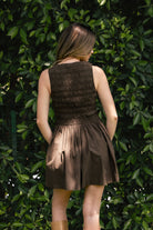 Woman wearing PRESLEY boat neck smocked body poplin mini dress featuring an elegant boat neckline, allover smocked bodice, sleeveless silhouette, gathered waist seam, functional front pockets, and soft cotton poplin fabric with a lightweight structured feel.