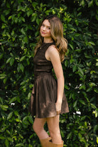 Woman wearing PRESLEY boat neck smocked body poplin mini dress featuring an elegant boat neckline, allover smocked bodice, sleeveless silhouette, gathered waist seam, functional front pockets, and soft cotton poplin fabric with a lightweight structured feel.