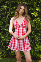 Woman wearing CHERYN V-neck gingham poplin mini dress featuring a classic gingham check pattern, scalloped lace trim neckline, sleeveless fit-and-flare bodice, decorative faux button detail, smocked back panel, hidden side zipper, and floral eyelet lace hem.