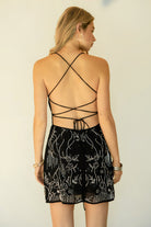 Woman wearing TIC TOC DL31853 VEDA chiffon sequin beaded lace-up mini dress featuring intricate floral bead and sequin embroidery, a flattering V-neckline with slim halter strap, open back design with adjustable lace-up tie, and a body-skimming mini silhouette for a radiant festival and summer night-out look.