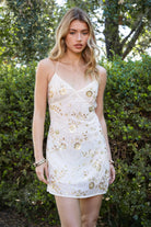 Woman wearing TIC TOC DL31853 VEDA chiffon sequin beaded lace-up mini dress featuring intricate floral bead and sequin embroidery, a flattering V-neckline with slim halter strap, open back design with adjustable lace-up tie, and a body-skimming mini silhouette for a radiant festival and summer night-out look.