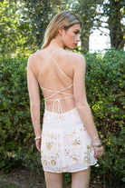 Woman wearing TIC TOC DL31853 VEDA chiffon sequin beaded lace-up mini dress featuring intricate floral bead and sequin embroidery, a flattering V-neckline with slim halter strap, open back design with adjustable lace-up tie, and a body-skimming mini silhouette for a radiant festival and summer night-out look.