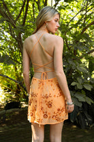 Woman wearing TIC TOC DL31853 VEDA chiffon sequin beaded lace-up mini dress featuring intricate floral bead and sequin embroidery, a flattering V-neckline with slim halter strap, open back design with adjustable lace-up tie, and a body-skimming mini silhouette for a radiant festival and summer night-out look.