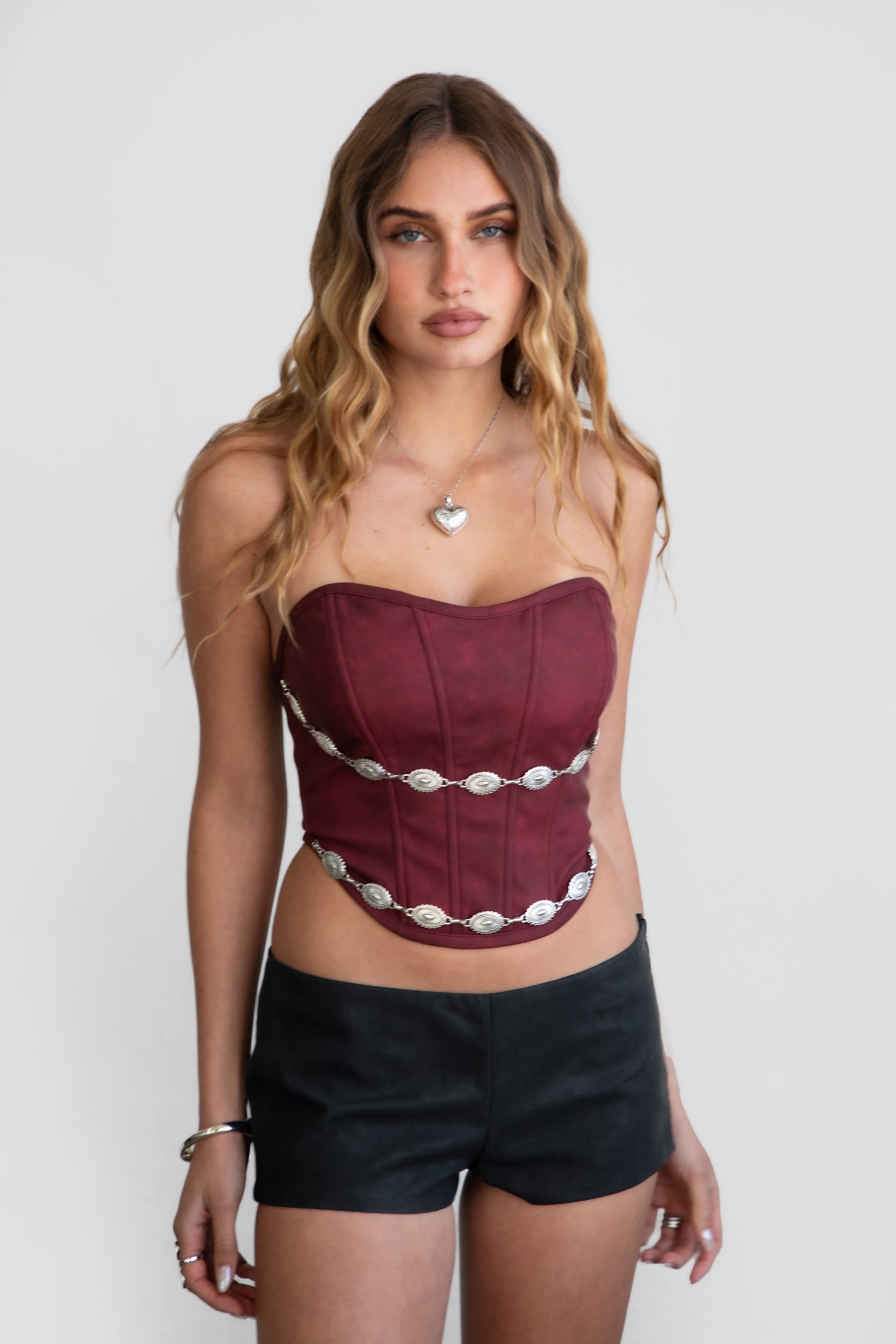 Model wearing LEIAH vegan leather micro shorts in black and brown, styled for a Western festival look