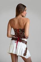 Model wearing red LOENA tapestry corset top with lace-up detailing, styled for a Coachella-inspired Western festival look