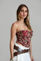 Model wearing red LOENA tapestry corset top with lace-up detailing, styled for a Coachella-inspired Western festival look