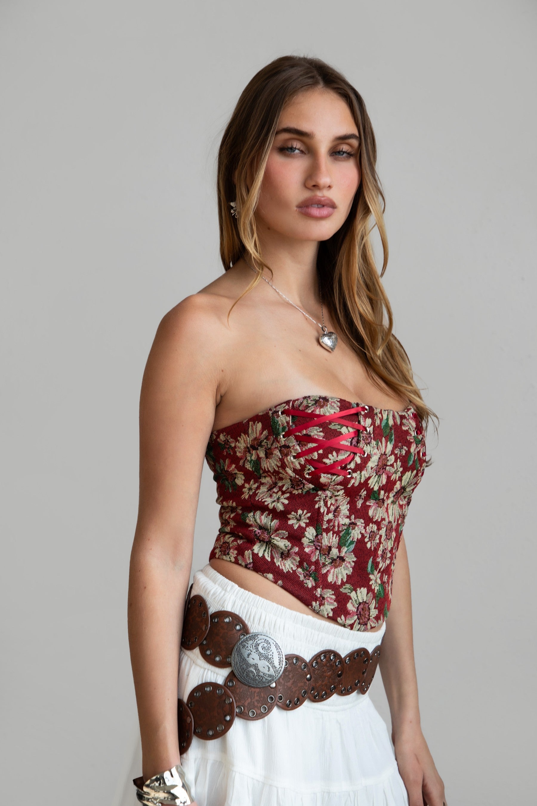 Model wearing red LOENA tapestry corset top with lace-up detailing, styled for a Coachella-inspired Western festival look