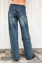 Woman wearing STERLING rhinestone straight leg jean featuring premium cotton denim, allover sparkling rhinestone embellishments, mid rise waist, relaxed straight leg silhouette, subtle vintage wash, classic five pocket design, zip fly, and button closure for statement styling.