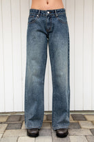 Woman wearing STERLING rhinestone straight leg jean featuring premium cotton denim, allover sparkling rhinestone embellishments, mid rise waist, relaxed straight leg silhouette, subtle vintage wash, classic five pocket design, zip fly, and button closure for statement styling.