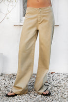 Woman wearing BOWDEN washed low rise wide leg denim pants featuring 100% cotton denim, relaxed vintage inspired silhouette, low rise waist, loose wide leg design, soft lived in washed finish, clean front styling, front zipper fly closure, classic back patch pockets, and full length fit.