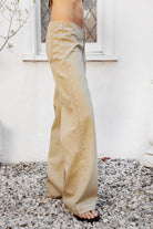 Woman wearing BOWDEN washed low rise wide leg denim pants featuring 100% cotton denim, relaxed vintage inspired silhouette, low rise waist, loose wide leg design, soft lived in washed finish, clean front styling, front zipper fly closure, classic back patch pockets, and full length fit.