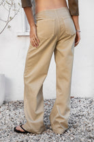 Woman wearing BOWDEN washed low rise wide leg denim pants featuring 100% cotton denim, relaxed vintage inspired silhouette, low rise waist, loose wide leg design, soft lived in washed finish, clean front styling, front zipper fly closure, classic back patch pockets, and full length fit.