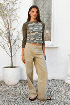 Woman wearing BOWDEN washed low rise wide leg denim pants featuring 100% cotton denim, relaxed vintage inspired silhouette, low rise waist, loose wide leg design, soft lived in washed finish, clean front styling, front zipper fly closure, classic back patch pockets, and full length fit.