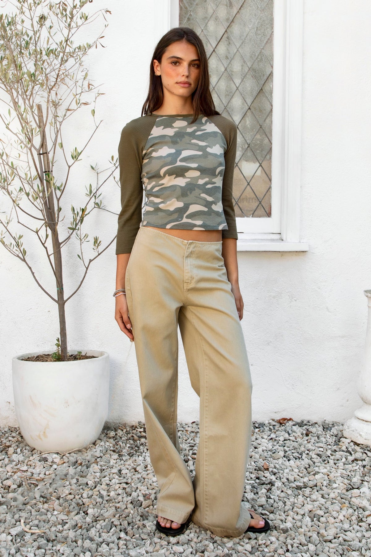 Woman wearing BOWDEN washed low rise wide leg denim pants featuring 100% cotton denim, relaxed vintage inspired silhouette, low rise waist, loose wide leg design, soft lived in washed finish, clean front styling, front zipper fly closure, classic back patch pockets, and full length fit.