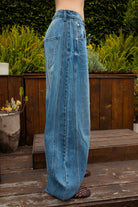 Woman wearing ROMII mid rise baggy fit barrel jeans featuring soft cotton lyocell denim, relaxed barrel leg silhouette, panel seam detailing, subtle knee tucks, classic five pocket design, zip fly, and button closure for modern casual streetwear styling.