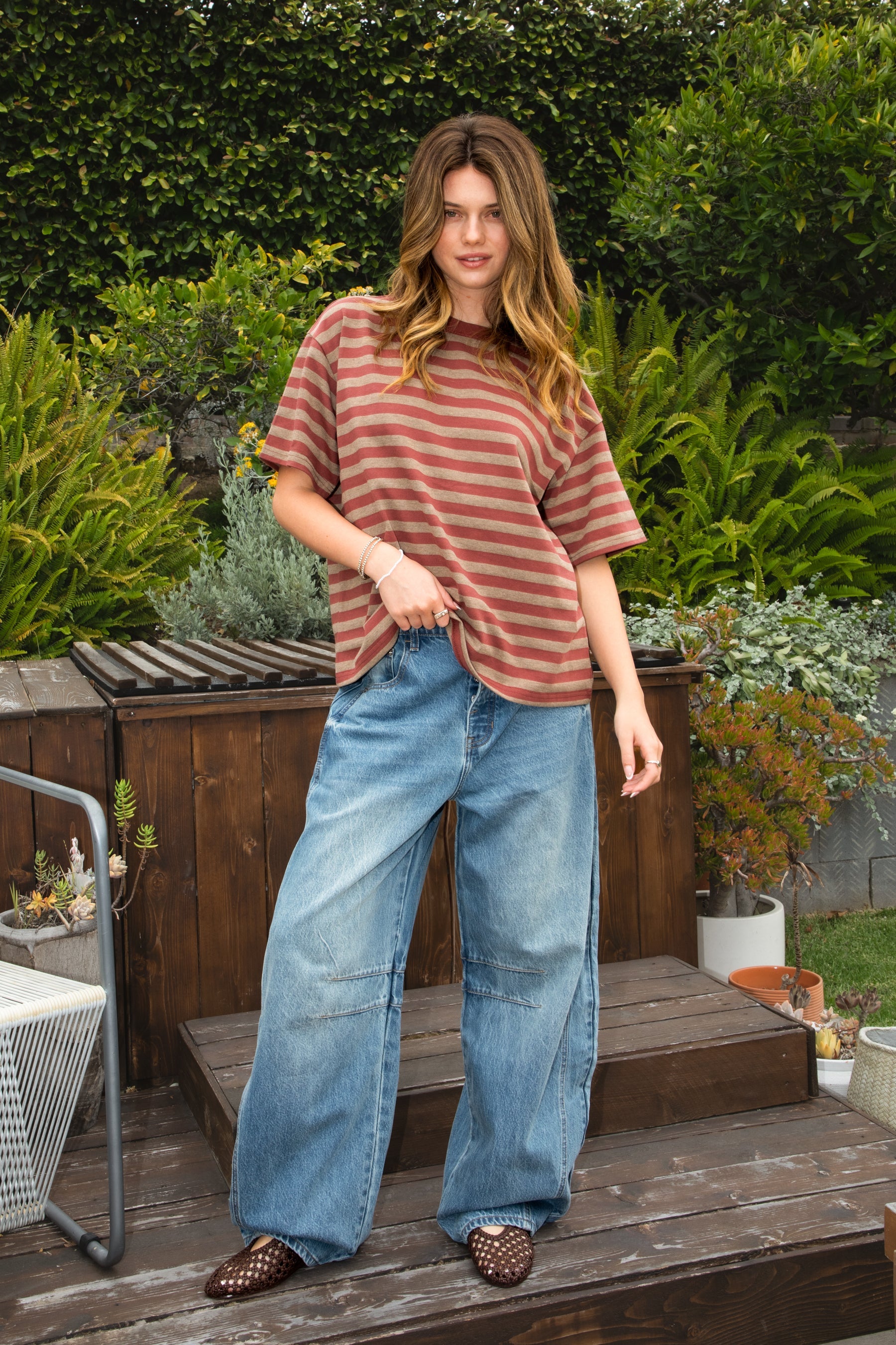 Woman wearing ROMII mid rise baggy fit barrel jeans featuring soft cotton lyocell denim, relaxed barrel leg silhouette, panel seam detailing, subtle knee tucks, classic five pocket design, zip fly, and button closure for modern casual streetwear styling.