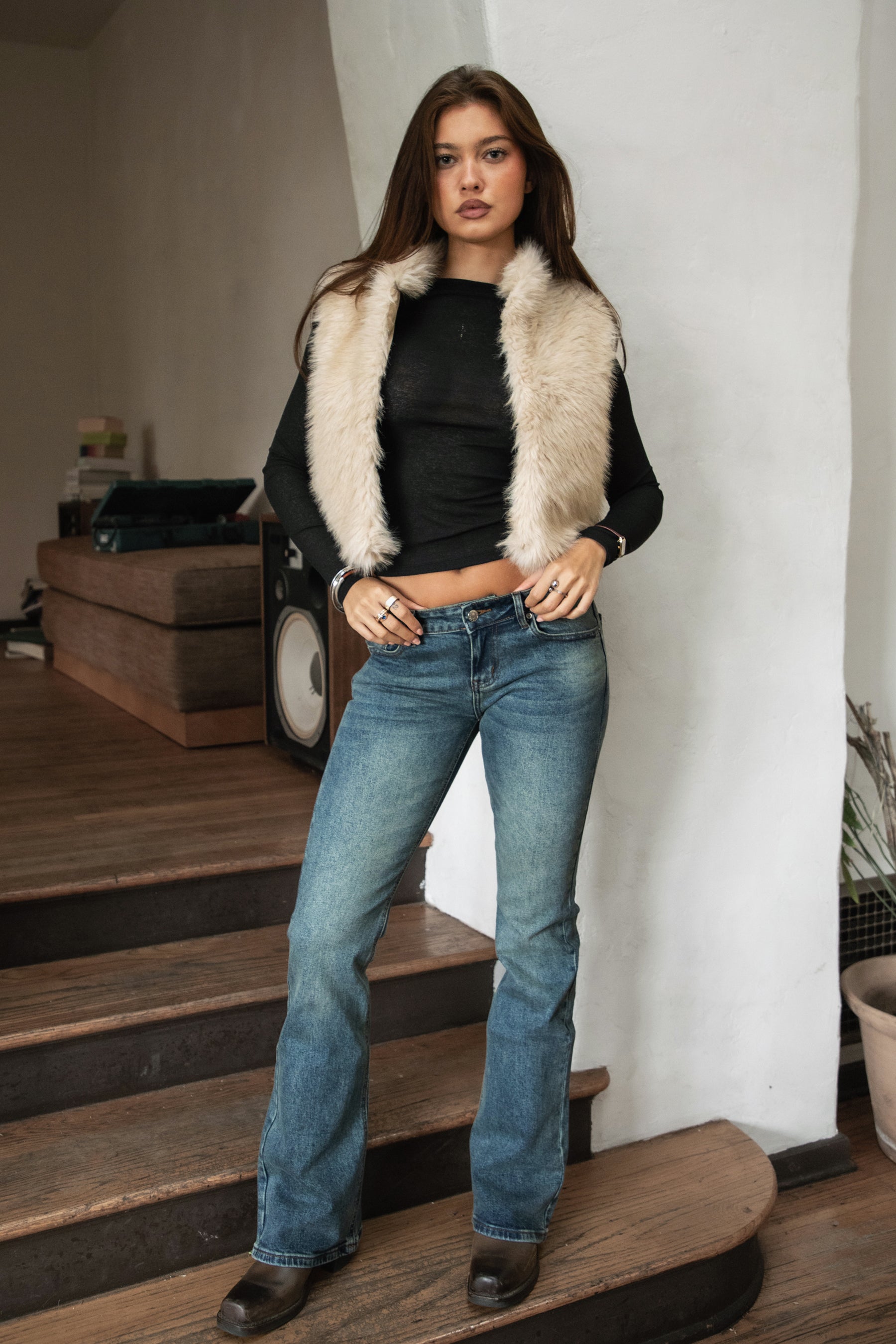 Woman wearing TIC TOC TA31834 BRIENNE faux fur vest in a natural tone; cropped open-front silhouette with plush texture, styled over a long-sleeve top and denim indoors.