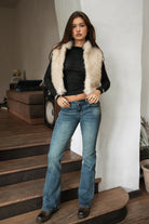 Woman wearing TIC TOC TA31834 BRIENNE faux fur vest in a natural tone; cropped open-front silhouette with plush texture, styled over a long-sleeve top and denim indoors.